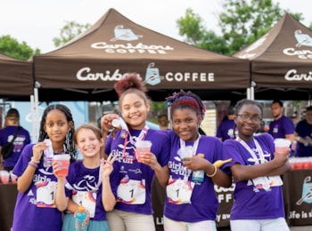 GOTR participants smile while hugging in front of Caribou booth at the 5K